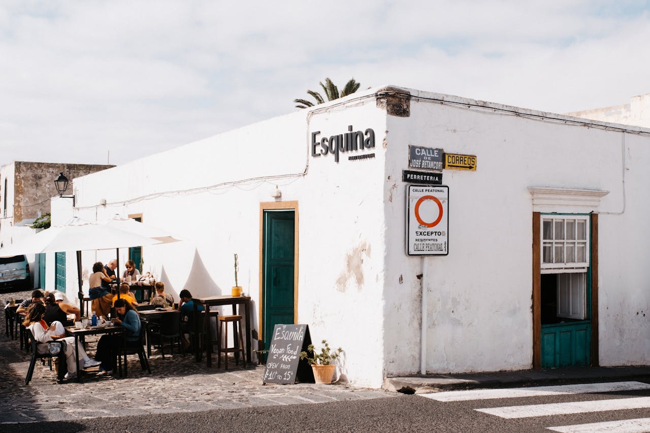 Cozy café on a bright city corner with people enjoying meals under parasols.